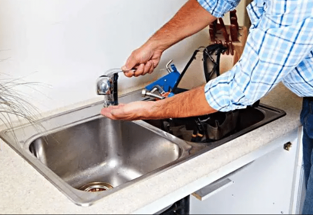 Professional plumber fitting a new faucet onto a bathroom sink.