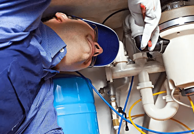 Professional technician diagnosing a faulty garbage disposal system.