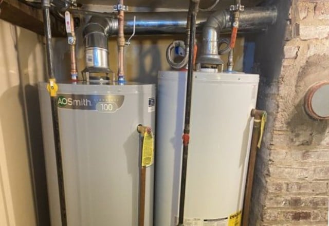 Two AO Smith commercial water heaters installed side by side with intricate piping, often requiring emergency water heater repair services.