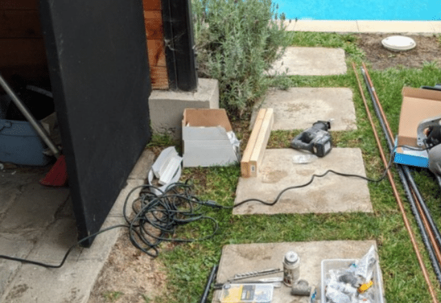 Various tools and equipment laid out on paving stones next to a home, setup for a residential gas line installation project.