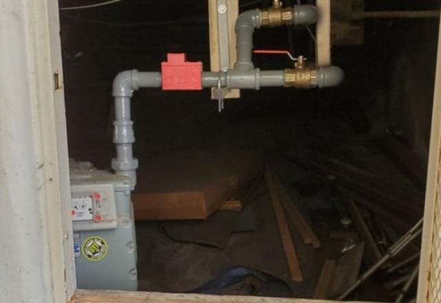 Gas meter and pipes with a red shut-off valve, a critical area for professionals repairing a gas line leak.