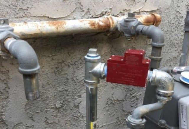 Outdoor gas line with a red lock-off tag, indicating recent repair work on a gas line leak.