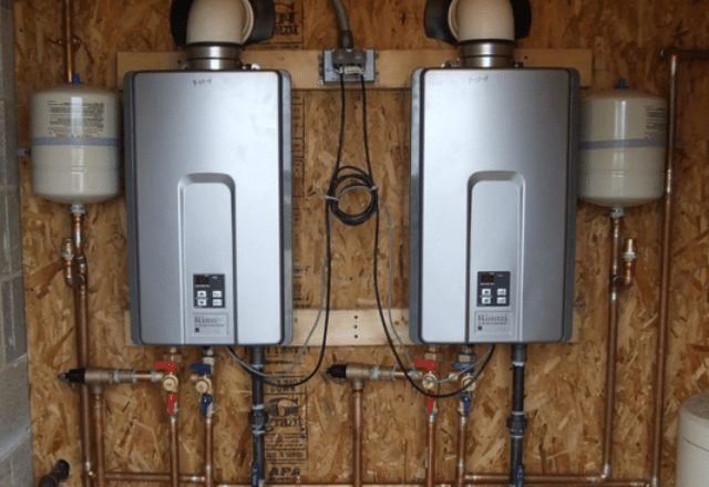 Two tankless electric water heaters mounted on a wooden wall with neat piping, indicating a professional installation.