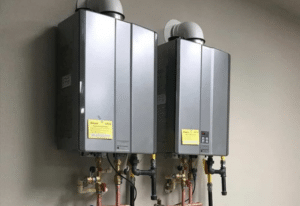 Pair of sleek tankless electric water heaters with modern design and labeled pipes, installed for efficient water heating.