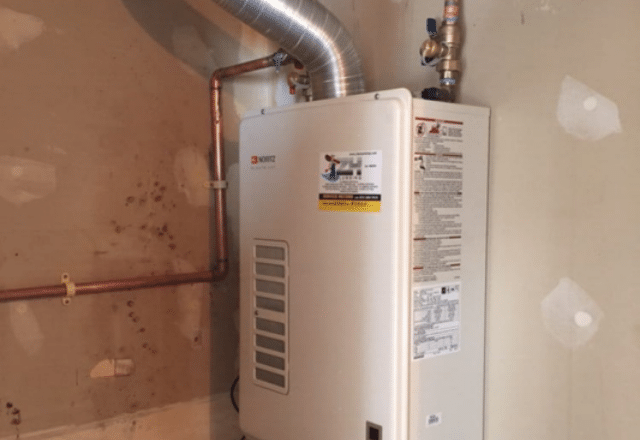 Noritz tankless electric water heater in a utility area, with clear safety instructions and a fresh installation look.