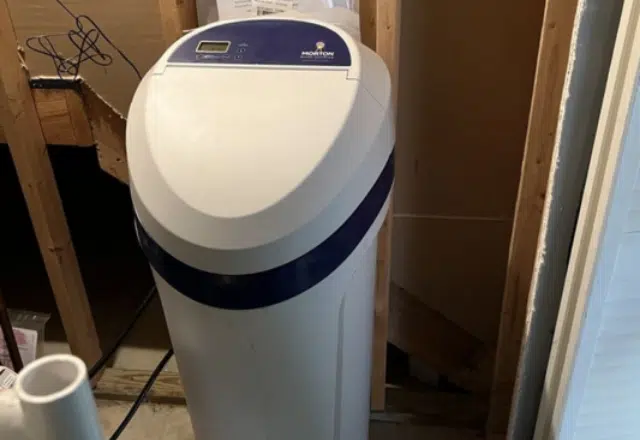 A standalone water softener appliance in a household utility corner, part of a water softener maintenance routine.