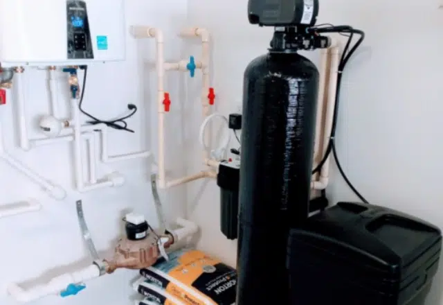 Neatly arranged water softener system with various pipes and a control valve, showcasing a well-maintained setup for water softener repair.