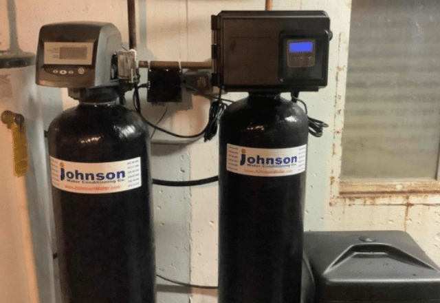 Two black water softener tanks with 'Johnson' labels and a digital display unit, indicative of professional water softener repair and service.