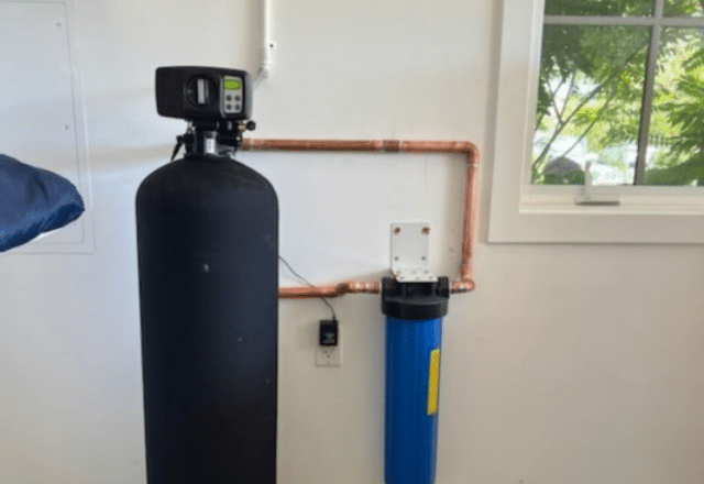 Residential water softener unit with a large control head and a blue filtration tank, part of a water softener repair and maintenance toolkit.