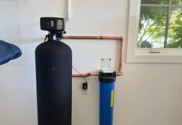 Residential water softener unit with a large control head and a blue filtration tank, part of a water softener repair and maintenance toolkit.