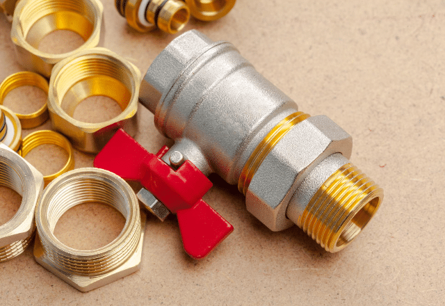 A close-up of a red-handled ball valve with brass fittings, representing the quality of supplies available in Sacramento's plumbing stores