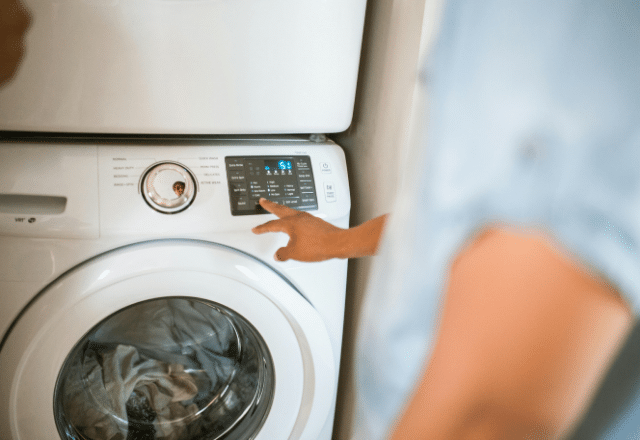 User operating a front-load washing machine with digital controls, highlighting the user-friendly aspect of contemporary washing machine drain plumbing.