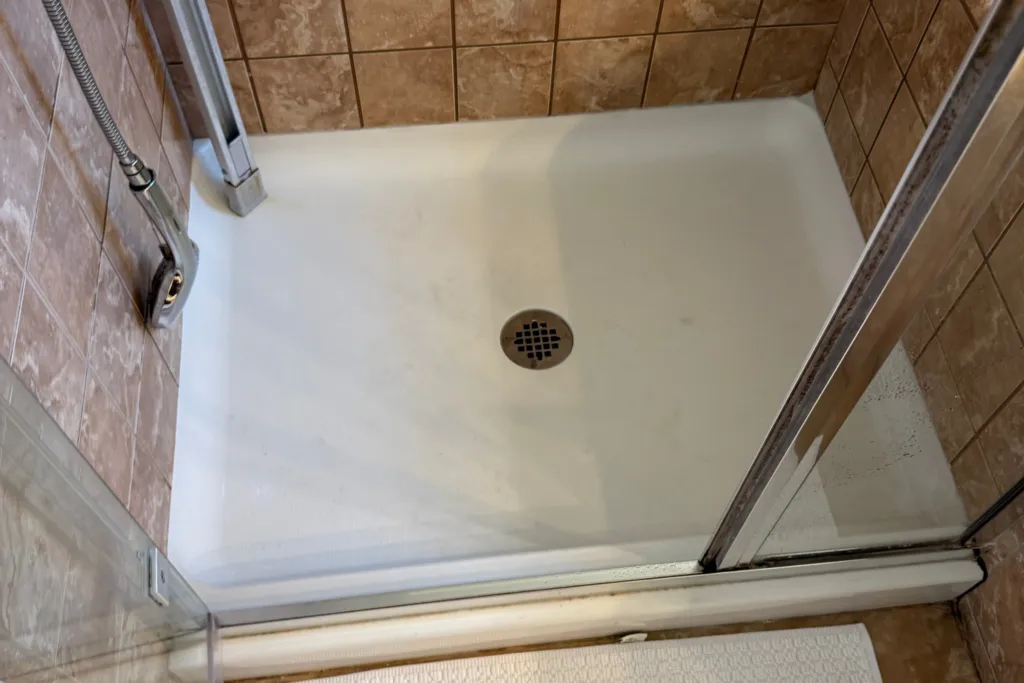 Plumber wearing gloves manually clearing a clogged kitchen sink drain