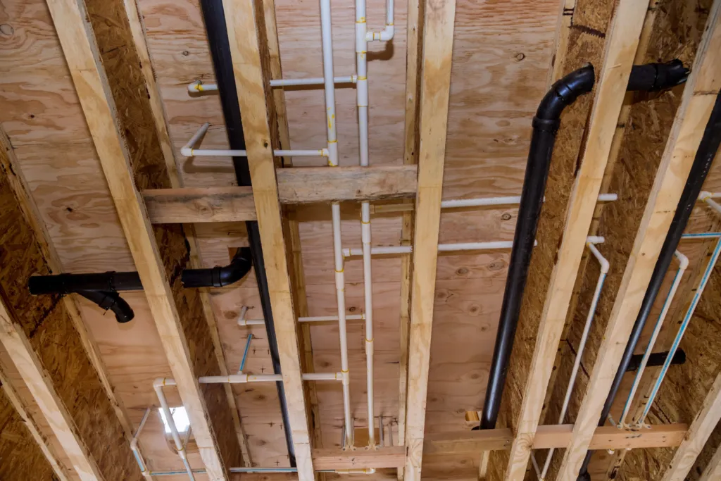 Exposed wooden framing showing newly installed PEX and copper pipes for whole-home repiping