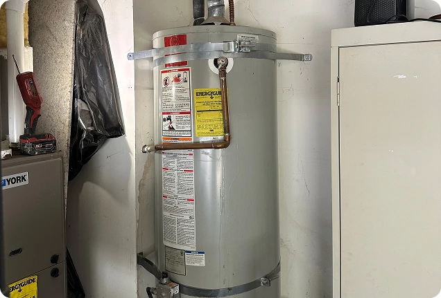 5 Star Plumbing technician installing a new gas water heater in a residential garage.