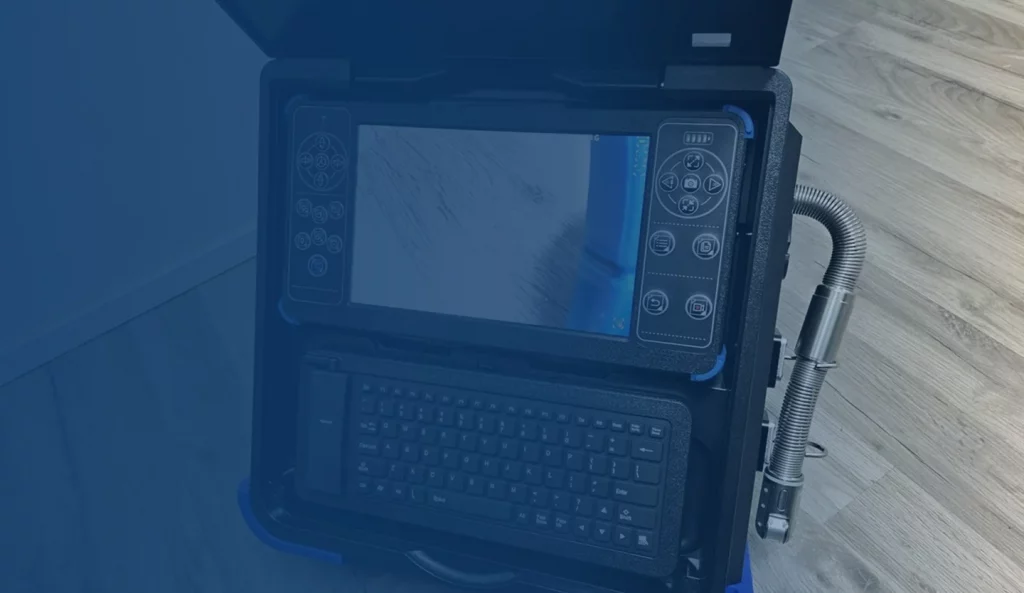 Rugged monitor displaying a live video feed from a sewer line camera inspection.