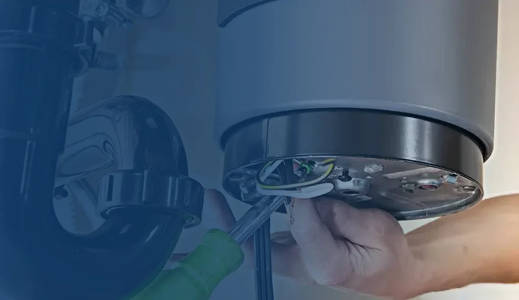 Plumber using a screwdriver on the mounting ring of a garbage disposal under a kitchen sink